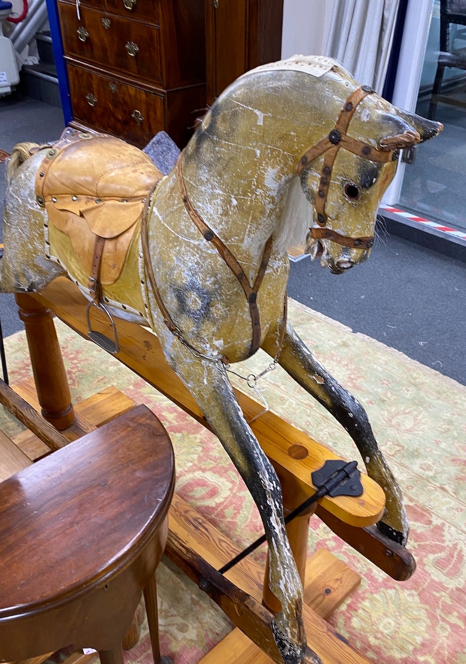 An early 20th century Ayers type dapple rocking horse with tan leather tack on pine safety frame, length 145cm, height 124cm